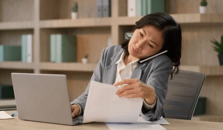 HR team member reviewing a request at a desk while on a call